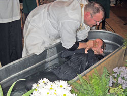 Father Ryan McCarthy, pastor of St. Michael Parish in Brookville and Holy Guardian Angels Parish in Cedar Grove, baptizes Ashley Tebbe on April 7 during St. Michael’s Easter Vigil Mass. Good communication among a parish’s pastor and parishioners interested in evangelization can help bring people to consider being welcomed into the full communion of the Church, says Peg McEvoy, archdiocesan associate director of evangelization and family catechesis. (Submitted photo)