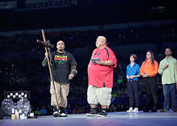 Holding a large crucifix, Ansel Augustine, left, talks with National Catholic Youth Conference emcee Jesse Manibusan during his presentation at the National Catholic Youth Conference in Indianapolis on the morning of Nov. 23 in Lucas Oil Staidum. (Photo by Rich Clark)