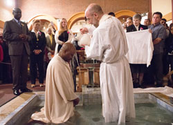 Father Todd Goodson, pastor of St. Monica Parish in Indianapolis, baptizes Gilles Noumsi during the parish’s Easter Vigil Mass on April 4. (© Denis Ryan Kelly Jr.)