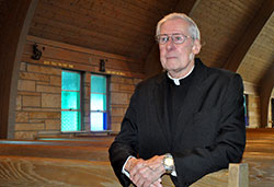 Father Donald Buchanan kneels in prayer on July 9 in American Martyrs Church in Scottsburg. He grew up as a member of the parish and celebrated his first Mass there after being ordained a priest on May 2, 1965. (Photo by Sean Gallagher)