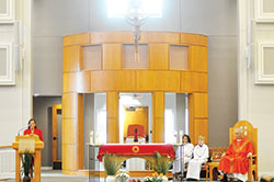 Sharon Albert proclaims the first reading during Palm Sunday Mass while retired Father David Lawler and two altar servers listen in St. Monica Parish’s restored and renovated church on April 9. The location of the Blessed Sacrament Chapel behind the altar was one of the changes made to the sanctuary. (Photo by Natalie Hoefer)