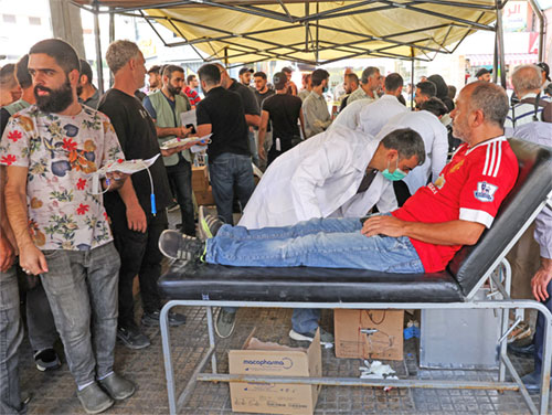 People gather as a man donates blood in Beirut Sept. 18, 2024, following pager detonations across Lebanon. The pagers exploded nearly simultaneously in Lebanon and Syria in an apparent Israeli operation targeting Hezbollah's communications network, killing at least 12 people and wounding nearly 3,000. (OSV News photo/Mohamed Azakir, Reuters)